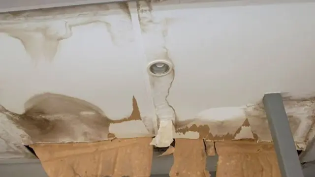 Water-stained ceiling with peeling paint around a light fixture
